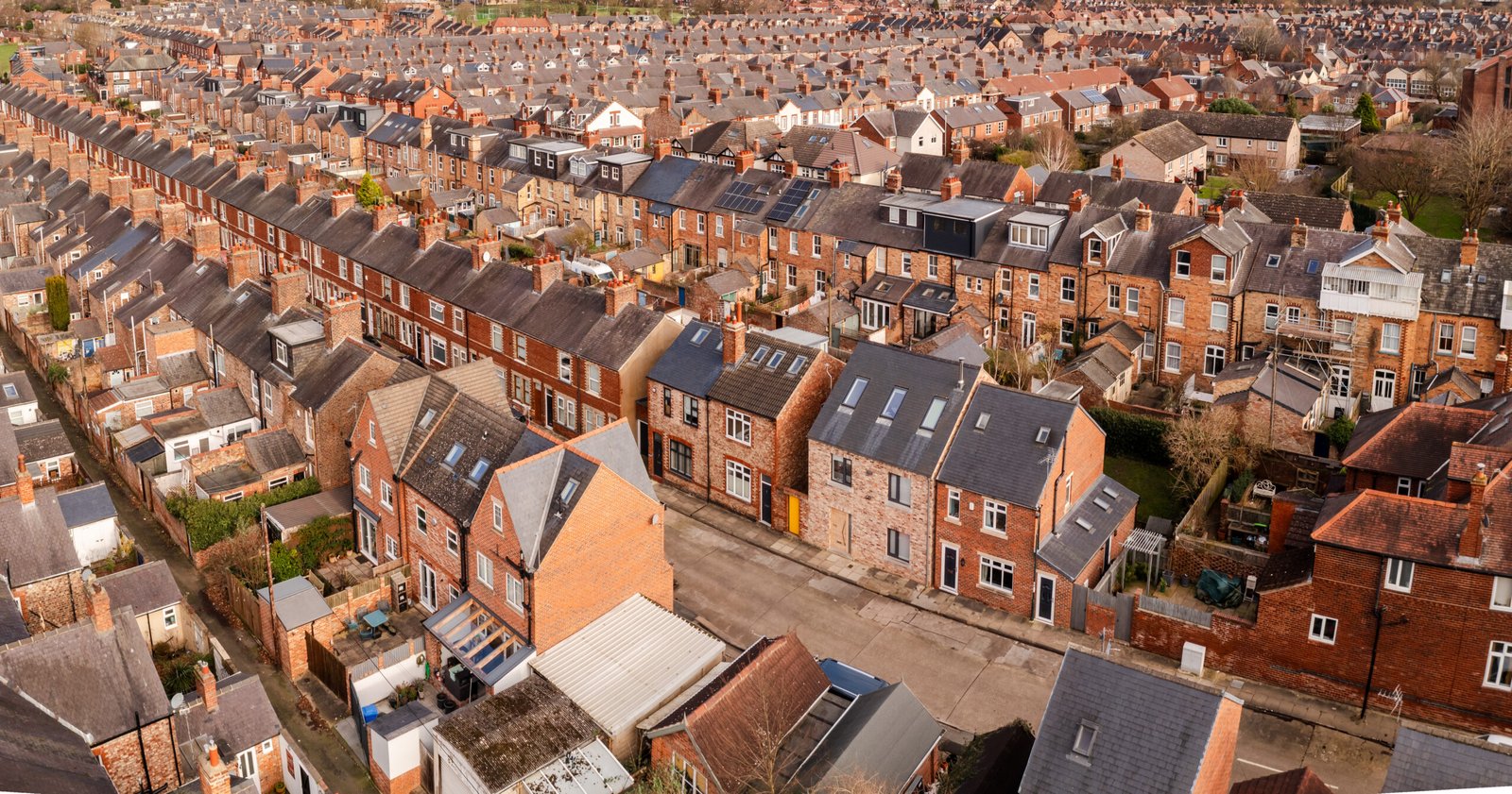 An aerial view above the rooftops of run down back to back terraced houses on a large residential estate in the North of England